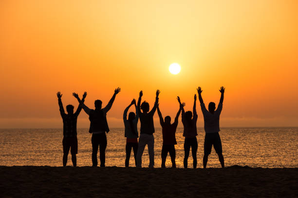 istock Silhouettes of people meditating on beach 674220240