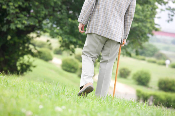 An old man walks with cane Park back
