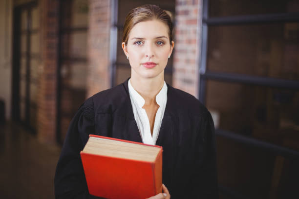 Confident female lawyer with book standing in office