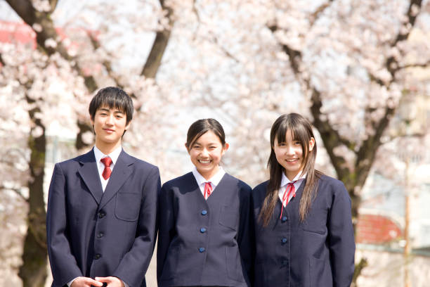 桜の花の下で笑っている男性と女性高校生 - 高校生 ストックフォトと画像