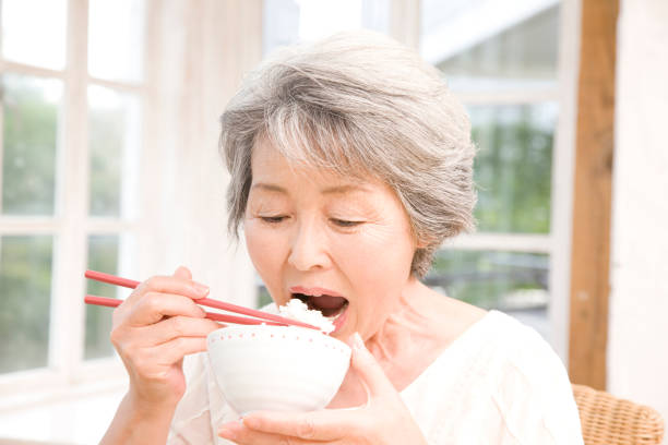 istock Senior woman eating white rice 674258620