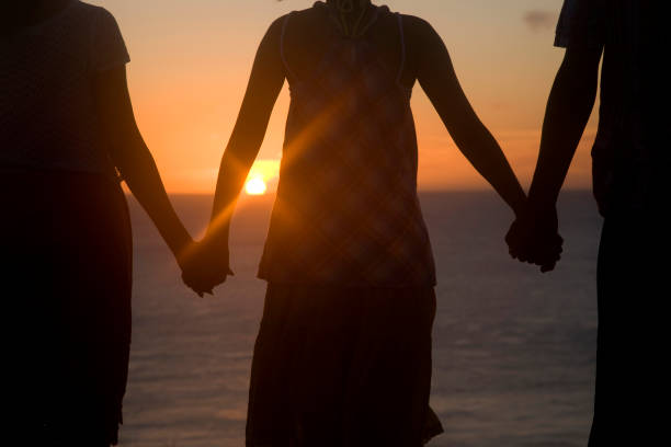 istock Clearvale hand, watching the setting sun men's and two women's rear view 674259080