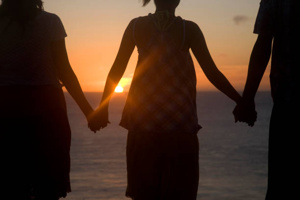 istock Clearvale hand, watching the setting sun men's and two women's rear view 674259096