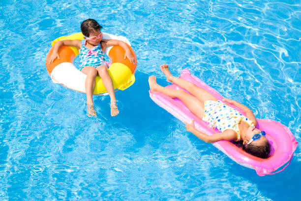 istock Two girls wearing a swimsuit in the float pool float 674280030