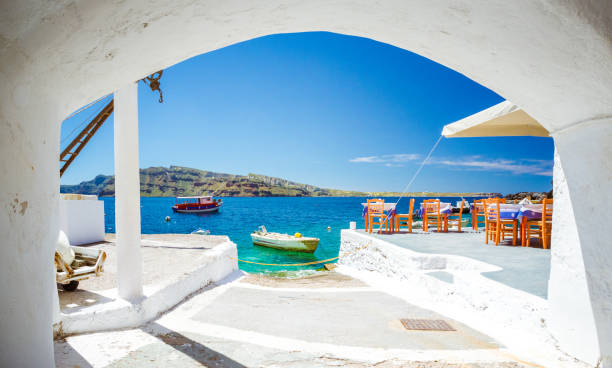 The old harbor of Ammoudi under the famous village of Oia at Santorini, Greece through a frame of an old arched building. The old harbor of Ammoudi under the famous village of Oia at Santorini, Greece through a frame of an old arched building. fira santorini stock pictures, royalty-free photos & images