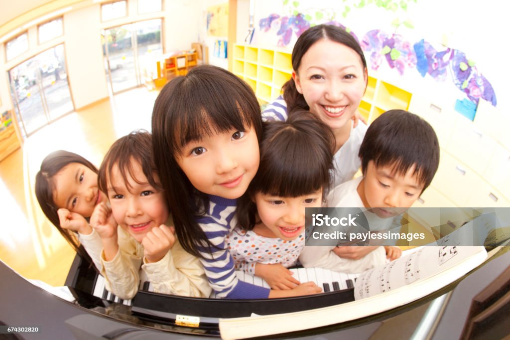 Nursery school and kindergarten smiles in front of a piano Adult Stock Photo