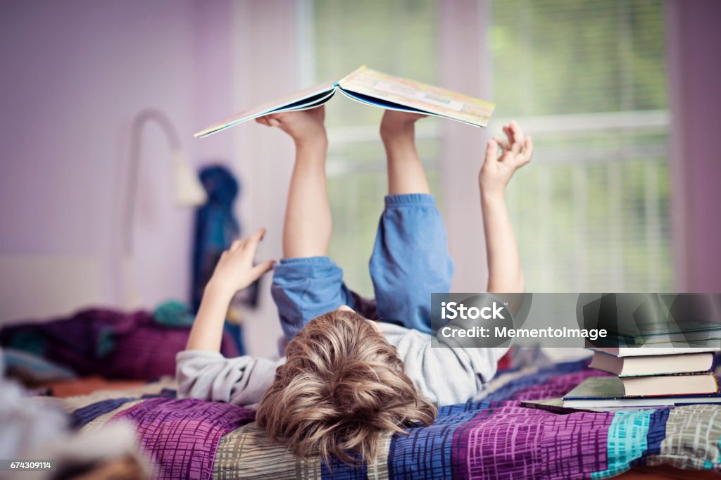 Boy reading Little boy lying on bed playing with books. Picture Book Stock Photo