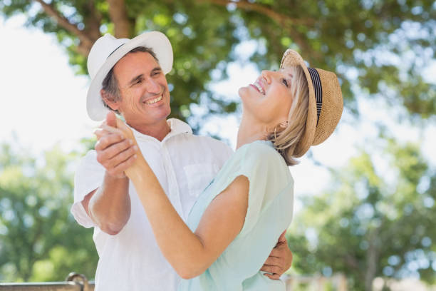 Cheerful couple dancing outdoors Cheerful couple dancing outdoors against trees middle aged couple dancing stock pictures, royalty-free photos & images