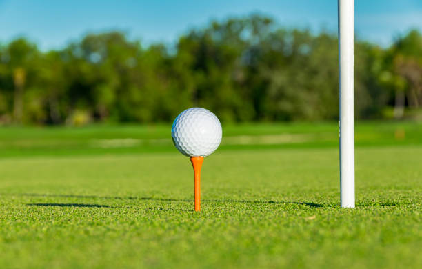 istock Golf ball on tee near golf hole on golf course 674319484