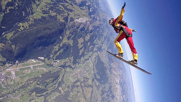 skydiver in freefall, on snowboard over mtns - freefall imagens e fotografias de stock
