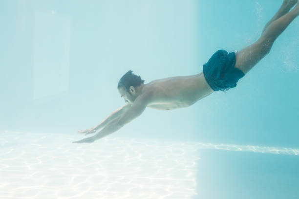 istock Shirtless man swimming under swimming pool 674349294