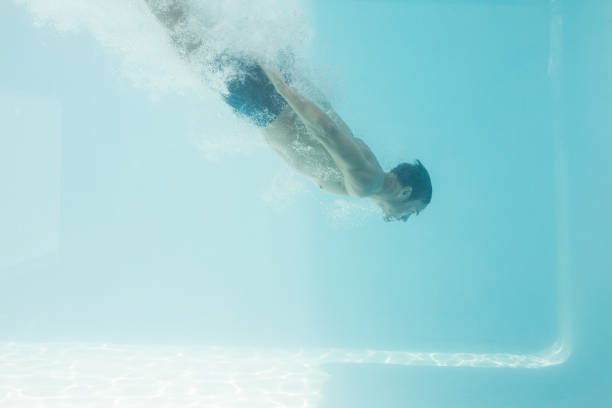 istock Shirtless man swimming underwater 674349296