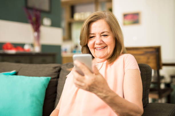 donna anziana che guarda il video sul suo telefono - grandparent adult smiling looking at camera foto e immagini stock