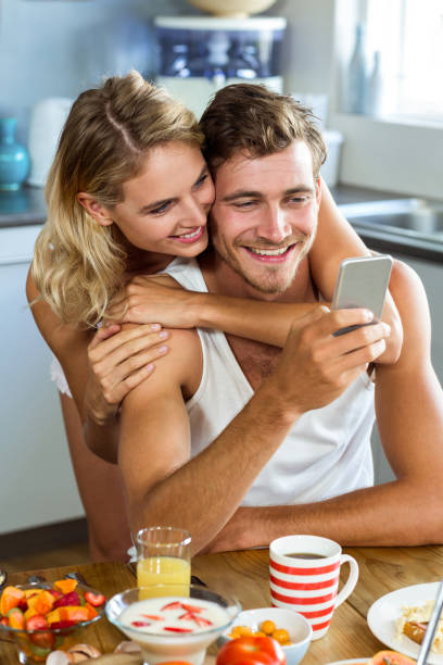 istock Woman embracing man using mobile phone at home 674361322