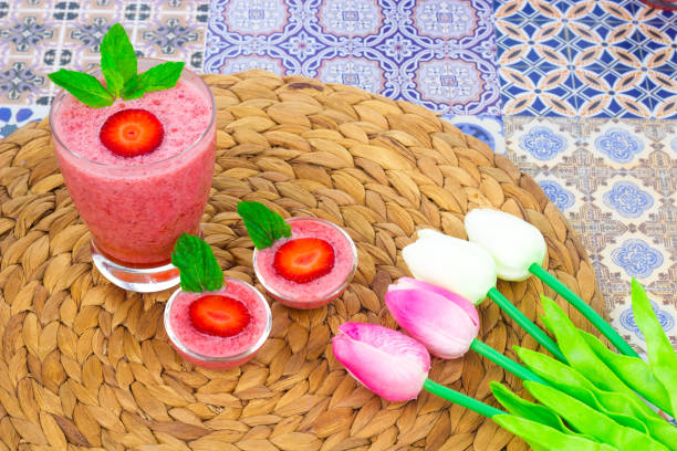 A cup of Strawberry Juice with mint leaves on an Oriental Colorful Background / Cup of Strawberry Juice on an Oriental Colorful Background with Flowers & mint leaves