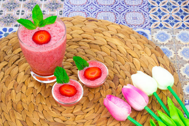 A cup of Strawberry Juice with mint leaves on an Oriental Colorful Background / Cup of Strawberry Juice on an Oriental Colorful Background with Flowers & mint leaves