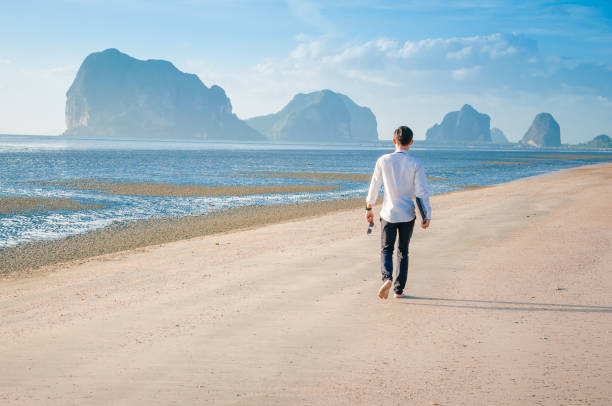 istock Relaxing Businessman using  laptop and smartphone on the beach 674387600