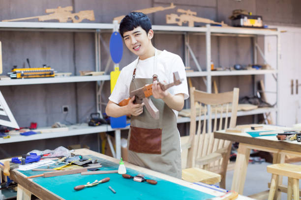 istock young male carpenter holding a wooden model plane in workshop 674390548
