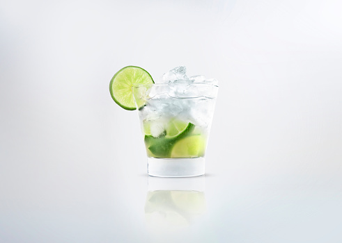 A glass of a alcoholic cocktail drink of caipirinha or mojito with fresh lemon on the glass and ice. Isolated on white background.