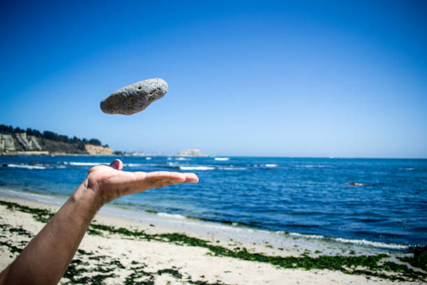 atirar uma pedra. fundo de praia - throwing stone human hand rock - fotografias e filmes do acervo