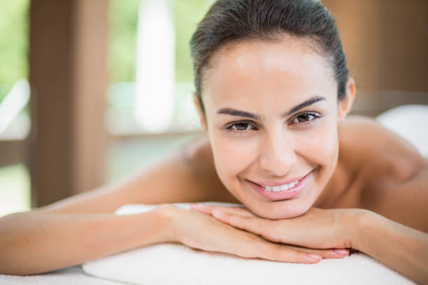 istock Portrait of young woman smiling while resting on massage table 674393956