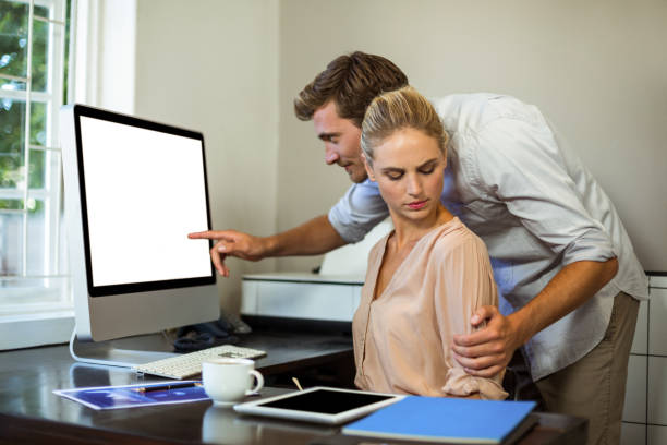 istock Man touching female colleague while working at office 674396592