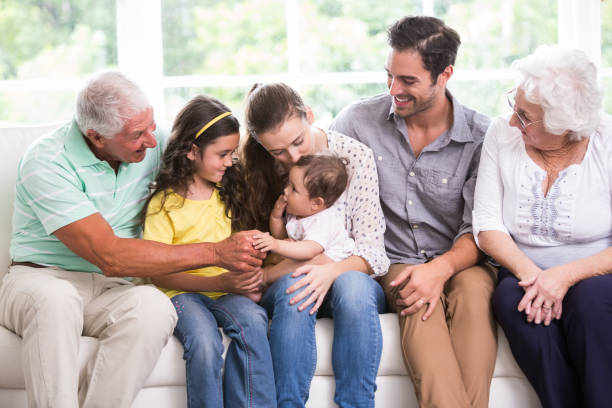 istock Smiling family playing with baby while sitting on sofa 674400580