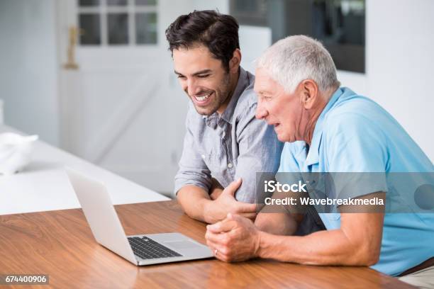 Smiling Father And Son Using Laptop Stock Photo - Download Image Now - Senior Men, Young Men, Computer