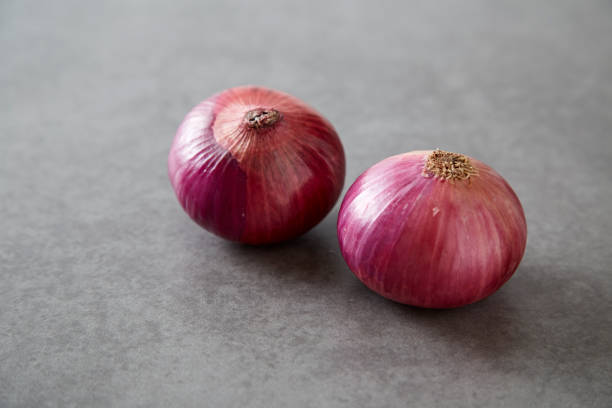 istock Red onions on Gray granite slab 674407034