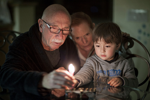 Familia judía iluminación Hanukkah velas en un candelabro para las fiestas photo