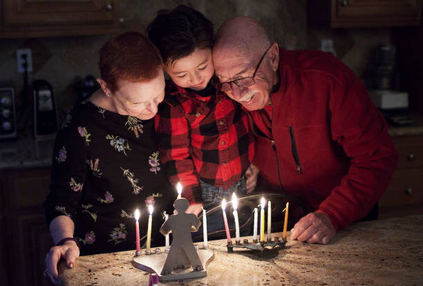 familia judía con abuelos y nieto iluminación hanukkah velas en un candelabro para las fiestas - enzo fotografías e imágenes de stock