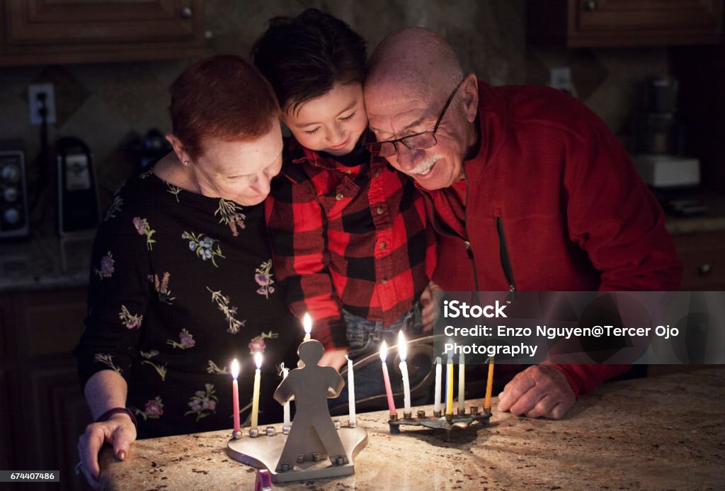 Família judia com granparents e neto iluminando velas em uma menorá para as férias - Foto de stock de Família royalty-free