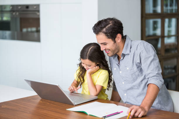 istock Smiling daughter working on laptop with father 674407816