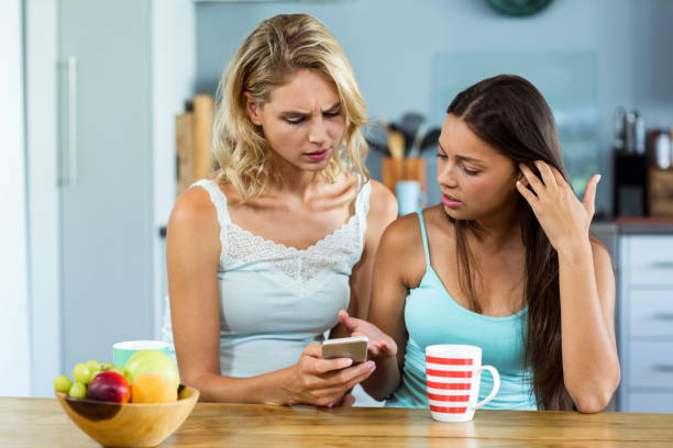 istock Female friends using mobile phone at home 674417494