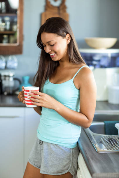 istock Smiling woman holding coffee cup in kitchen 674417532