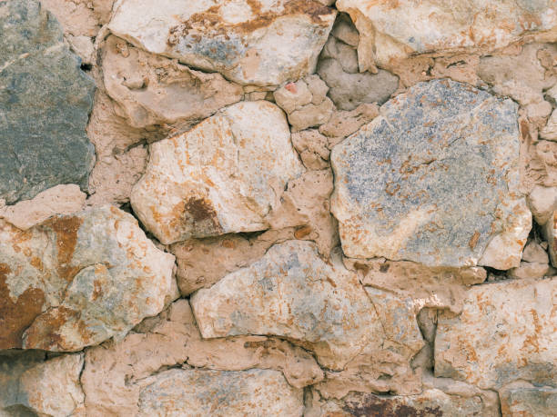 istock The crumbling wall of large stones with cement. 674420370