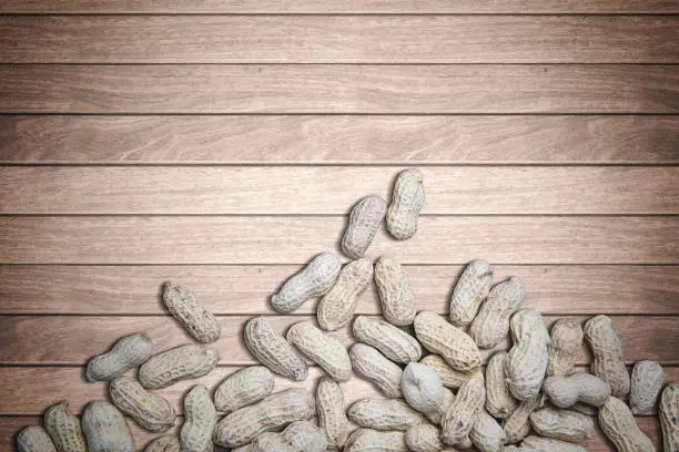 High angle of crunchy groundnuts on the wooden background, concept of healthy food
