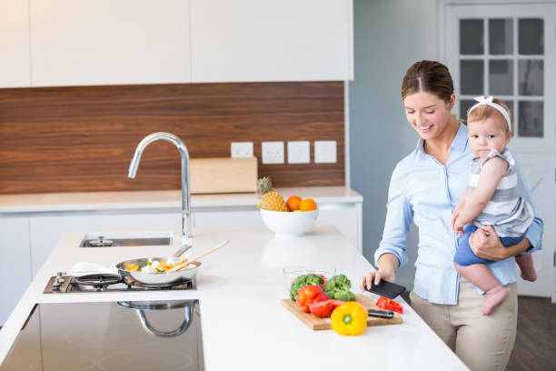 istock Woman carrying daughter by kitchen counter 674431120