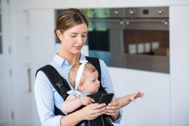 istock Woman using mobile phone while carrying baby girl 674431178