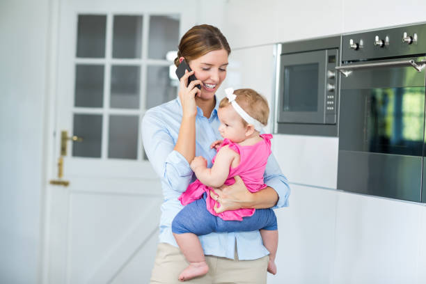 istock Woman talking on cellphone while carrying baby girl 674431430