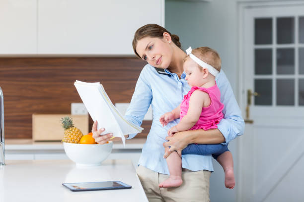 istock Woman reading documents while carrying baby girl 674432170