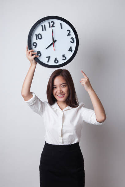 istock Young Asian business woman point to a clock. 674434424