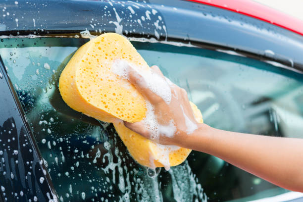 istock hand with yellow sponge washing car 674435368