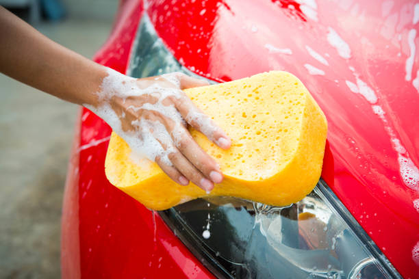 istock hand with yellow sponge washing car 674435372