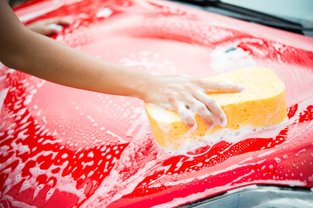 istock hand with yellow sponge washing car 674435402
