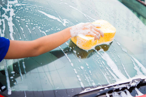 istock hand with yellow sponge washing car 674435438