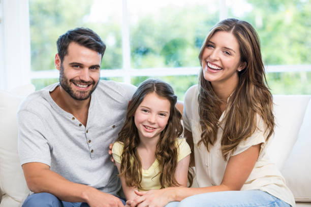 istock Happy couple sitting with daughter on sofa 674448456