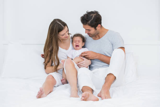istock Parents with crying baby sitting on bed 674453058