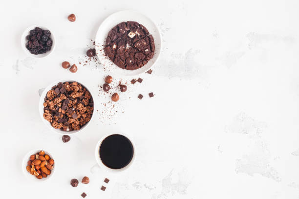 Cups of coffee, chocolate cake, chocolate muesli on white background
