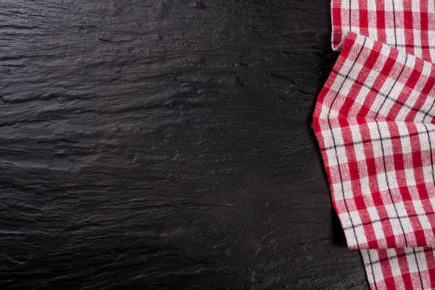 istock Red checkered tablecloth on a dark stone background with copy space for your text. Top view 674453520